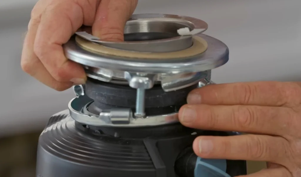 Close up of hands inspecting a garbage disposal not working showing the mounting ring flange and rubber gasket during repair