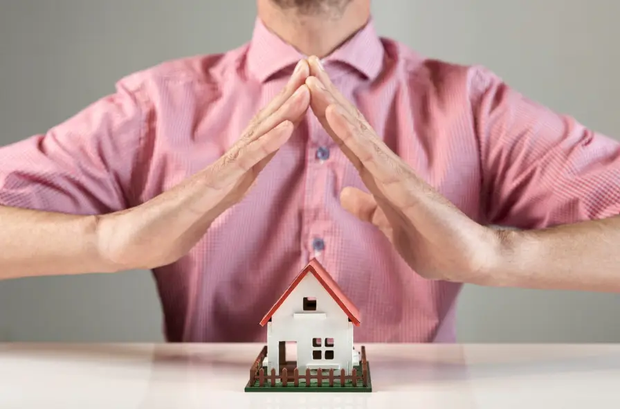 Homeowner shielding a model house symbolizing Old Republic home warranty protection for plumbing repairs and emergencies
